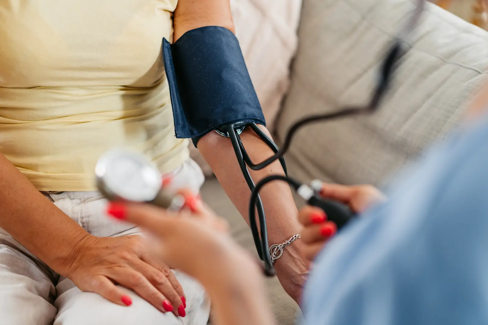 A clinician checks a seated patient's blood pressure with an arm cuff and gauge.